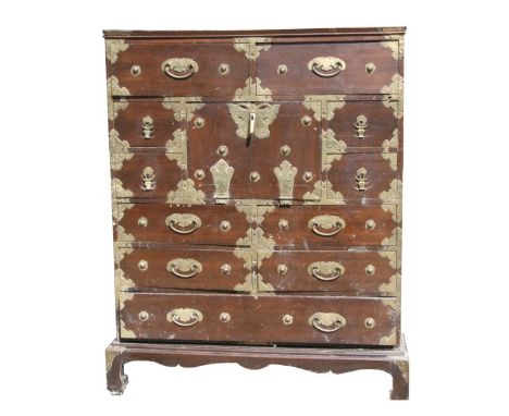 A late 19th/Early 20th Century Korean brass mounted hardwood cabinet with central fall flap and an arrangement of eleven draw