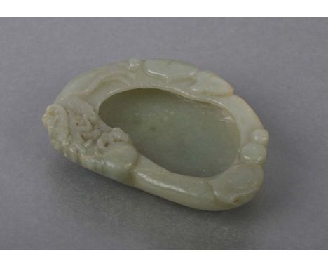 A Chinese jade / hardstone brush washer decorated with a dragon and lily pads, on a hardwood stand, 9cms wide.