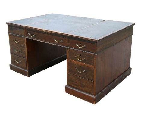 An Edwardian mahogany partners desk with an arrangement of drawers and cupboards, on a plinth base, 152cms wide.