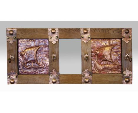 An arts and craft wall mounted coat rack with oak frame, central mirror and two hand beaten copper panels of Viking ships.