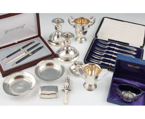 A collection of hallmarked silver items, to include a pill box, a rattle, a pair of weighted dwarf candlesticks, a 'Coronatio