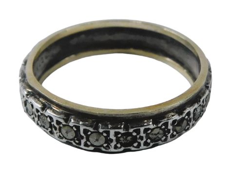 An eternity ring, the central silvered design set with marcasite, bordered by gold border, stamped 9ct gold sil, some stones 