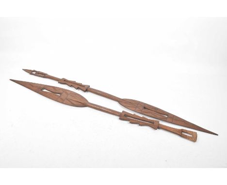 A pair of decorative carved wooden African spearsTapered pierced and paddle like spears carved with geometric design extendin