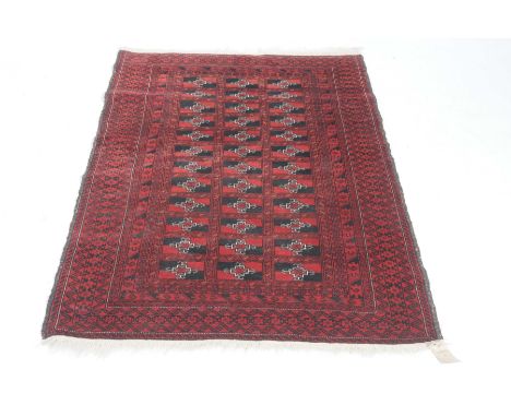 A ruby-red Afghan style rugThe central rectangular medallion filled with a series of black and red panels set within geometri