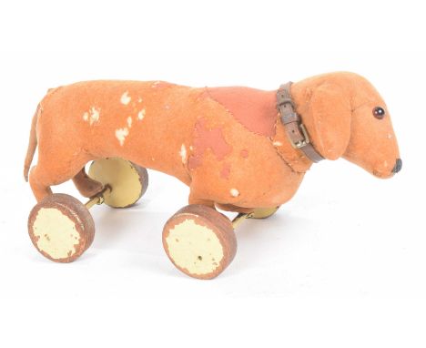 An early Steiff  push along Dachshund With orange brown felt body, glass button eyes and small pin to left ear on four wooden