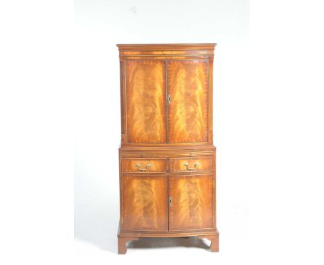 A Georgian style mahogany serpentine drinks cabinet by ReproduxWith two flame mahogany doors above a sliding tray and two fri