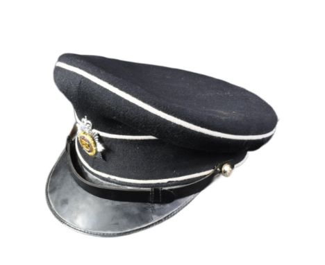 A post war vintage Royal Army Service Corps officers dress uniform peaked cap. Dark blue twilled wool with white piping and a