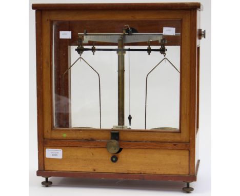 An early 20th Century Apocathy scales, satinwood cased, the sash glazed door opening on weights, fitted with a drawer to base