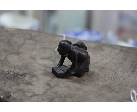 An antique carved wood netsuke of a kneeling figure of a man with a rat on his back, signature to base, 1 1/2" high