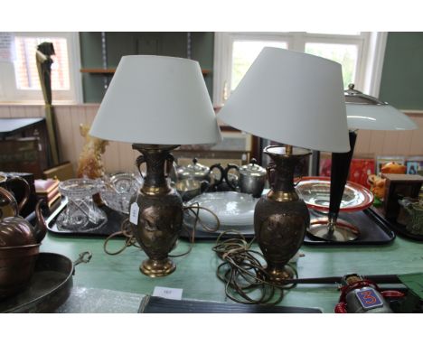 A pair of metal based Chinese style table lamps decorated with raised birds, dragon motif to top