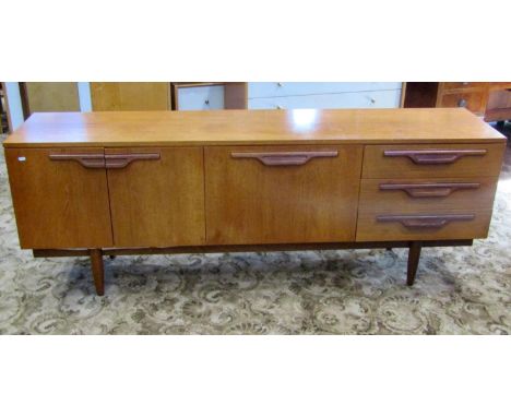 A long and low retro teak sideboard, partially enclosed by three doors and a tower of three drawers, with moulded handles and