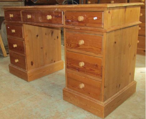 A stripped pine kneehole twin pedestal dressing table/desk in the Victorian style, fitted with an arrangement of nine drawers