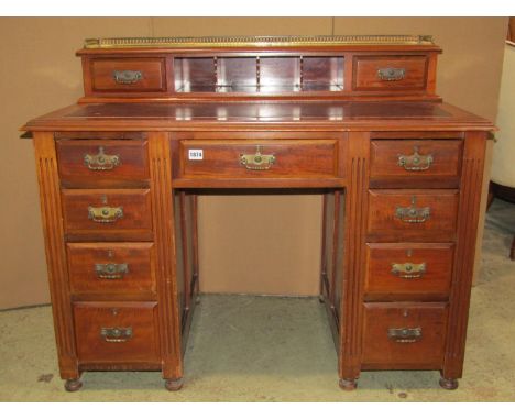 An Edwardian walnut kneehole twin pedestal writing desk fitted with an arrangement of nine drawers, flanked by fluted detail 