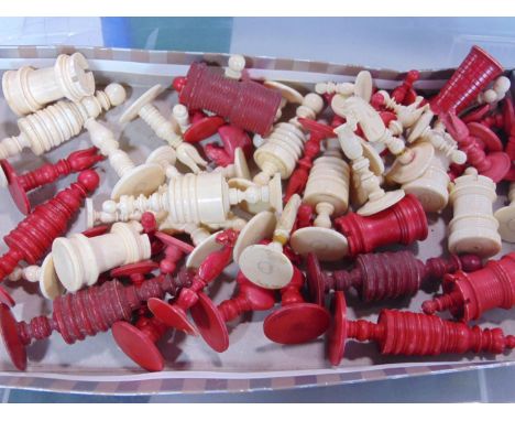 A large collection of 19th century turned ivory chess pieces in red and white, incomplete sets 