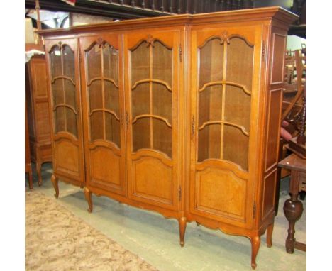 A large medium oak floorstanding, four door shallow breakfront bookcase, partially glazed with segmented adjustable shelved i