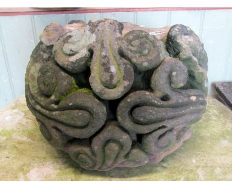 A weathered natural stone corbel with deep carved scrolling foliate detail, 38 cm in diameter approx 