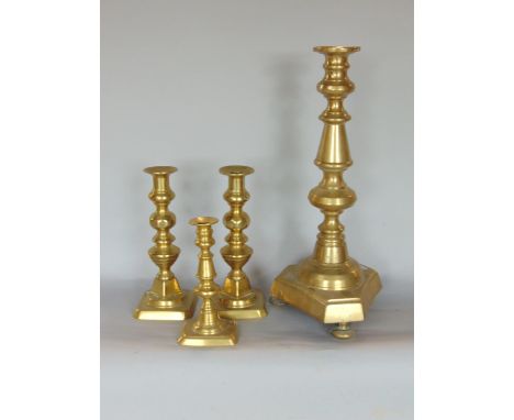 A large turned brass floor candlestick or Prickett stick, 48cm high, together with a further pair of candlesticks and one oth