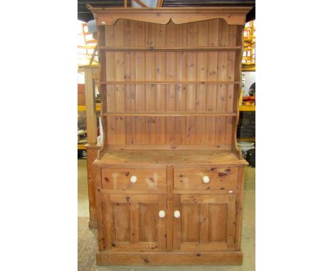 A Victorian style stripped pine kitchen dresser, the base enclosed by a pair of twin moulded rectangular panelled doors benea