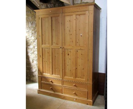 A Victorian style stripped pine wardrobe enclosed by a pair of three quarter length quarter moulded panelled doors over four 