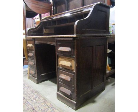 An early 20th century oak kneehole twin pedestal roll top desk, the S shaped tambour roll now enclosing a vacant interior ove