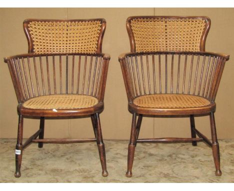 A pair of early 20th century light weight, stained beechwood stick-back elbow chairs, with cane panels, raised on splayed tur