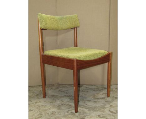 A set of four mid-20th century teak framed dining chairs with light green upholstered drop-in seats and rail backs, raised on