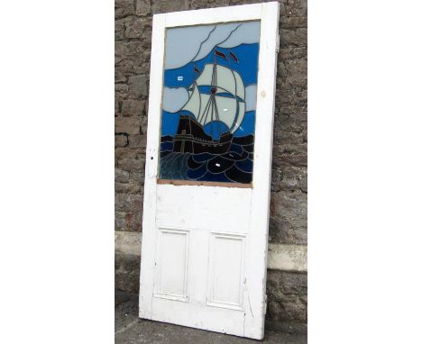 A reclaimed 1930s painted pine door, partially enclosing a coloured leaded light panel of a galleon at full sale, 80 cm wide 