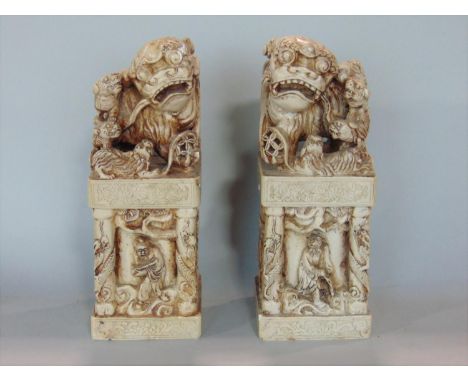 A pair of Chinese carved soapstone dogs of fo seals, mounted by various carved dogs upon temple columns, each carved with a s