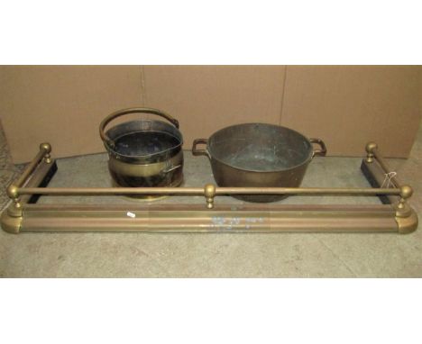 A Victorian style adjustable brass fender, a heavy bell metal two handled pan, and a brass helmet shaped coal scuttle (3) 