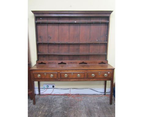 A Georgian oak Welsh dresser and plate rack, the base enclosed by three frieze drawers, crossbanded in walnut, raised on squa