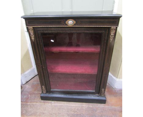 A Victorian pier cabinet with ebonised finish, enclosed by a glazed panel door, with string inlay detail and applied cast bra