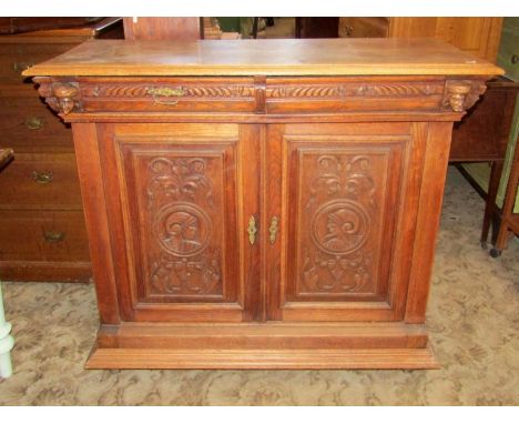 A 19th century carved oak side cupboard/buffet with portrait panels, scrolling acanthus and face mask detail, fitted with two