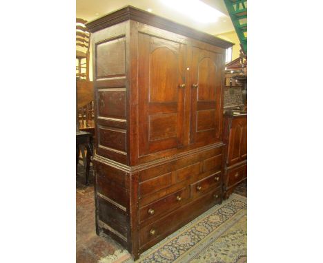 An 18th century oak livery cupboard in two sections, the upper section enclosed by a pair of panelled doors, the lower sectio