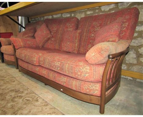 An Ercol medium elm lathe back sofa and matching armchair, with alternating, repeating floral patterned upholstered cushions 