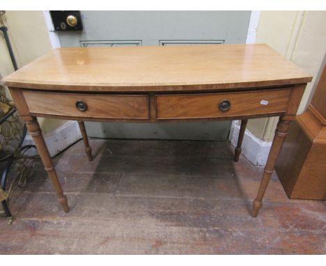 A regency mahogany bow-fronted side table fitted with two frieze drawers, brass ring handles and raised on turned tapering su