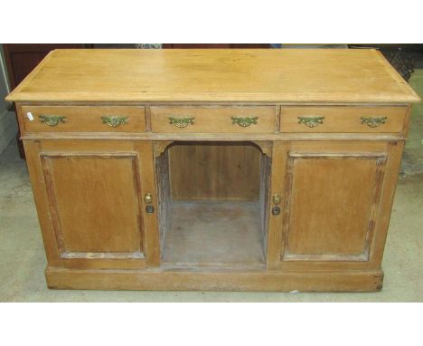 A Victorian stripped pine dresser fitted with three frieze drawers over a pair of cupboards flanking an open fronted compartm
