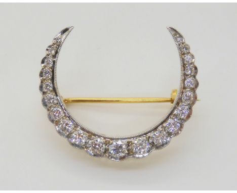 A DIAMOND CRESCENT MOON BROOCH set with estimated approx 0.70cts of brilliant cut diamonds, to the galleried yellow and white