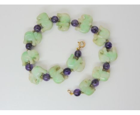 A JADE ELEPHANT BRACELET strung with twelve Chinese green hardstone elephants, inter spaced with amethyst beads. Most elephan