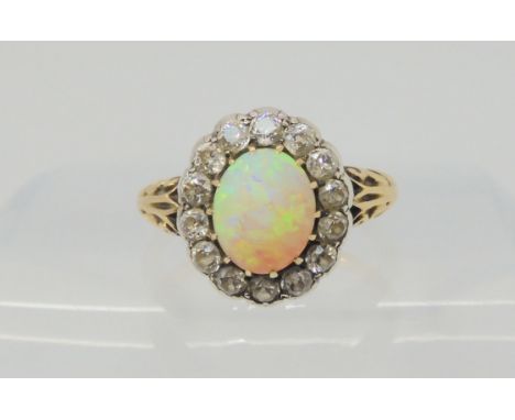 AN OPAL AND DIAMOND RING set with a high domed opal of approx 8.8mm x 7.1mm x 4.1mm, surrounded with a halo of old cut diamon