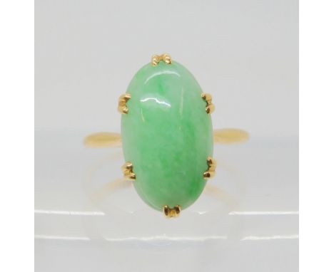 A CHINESE GREEN HARDSTONE RING mounted in bright yellow metal, the hardstone measures approx 16mm x 9.4mm x 4.2mm, finger siz