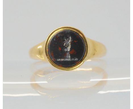AN 18CT GOLD INTAGLIO SIGNET RING set with an intaglio carved bloodstone, depicting a hand holding a heart. Diameter of seal 