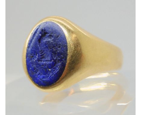 AN INTAGLIO SIGNET RING set with a carved lapis lazuli, with Motto & Crest, 'watch over me'. Finger size K, weight 7.4gms Con