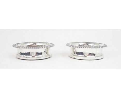 A MATCHED PAIR OF GEORGE IV SILVER WINE COASTERS with gadrooned rims and turned wooden inserts, with blank silver buttons to 