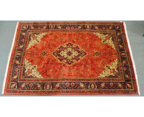 A TERRACOTTA GROUND TABRIZ RUG with red and cream central medallion, cream and dark blue spandrels and dark blue floral borde