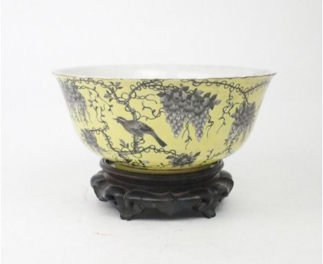 A CHINESE YELLOW GROUND BOWL  Painted with a bird amongst wisteria,within gilt rims red seal and character marks, 23cm diamet