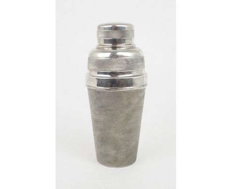 A GEORGE V SILVER COCKTAIL SHAKER of typical form, the body engine turned with a mesh texture, the strainer and cover part ma