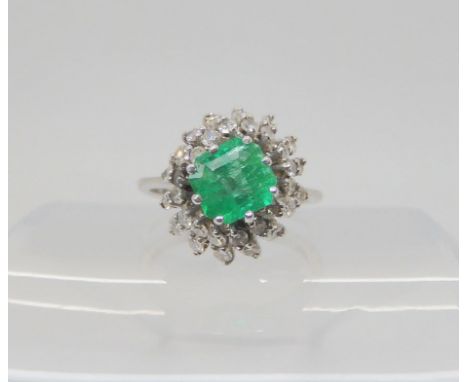 AN EMERALD & DIAMOND CLUSTER RING set with a 6.1mm x 6.4mm x 4.4mm step cut emerald, and estimated approx 0.48cts of eight cu