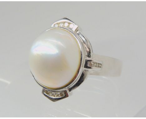 A MABE PEARL &amp; DIAMOND RING set in 14k white gold, the mabe pearl measures 14mm in diameter and is channel set with diamo