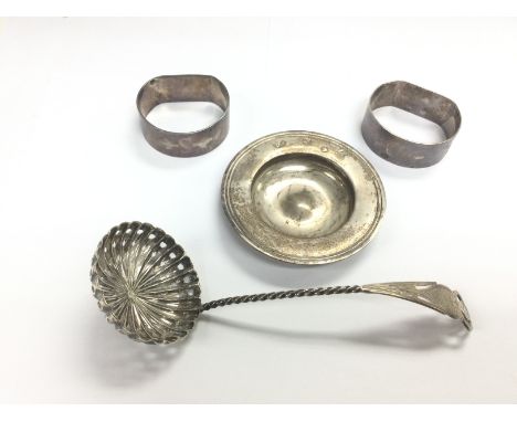 Four silver items comprising a sugar ladle, pin tray and two napkin rings. Shipping category D.