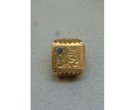 A gold (unmarked) gentleman's signet ring monogrammed and set with a light blue sapphire, approximately 10.9g.